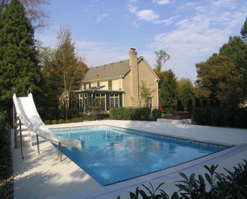 an in-ground pool with a slide and automatic cover